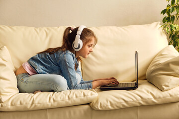 Obraz premium Kid girl with headphones looking video lesson