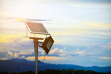 Mini solar cell or photovoltaic panel and floodlight led installed on metal pole, blurred mountain...