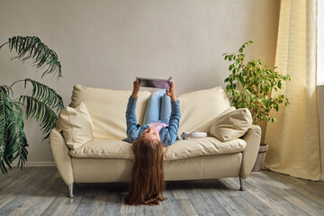 little girl lying upside down on sofa