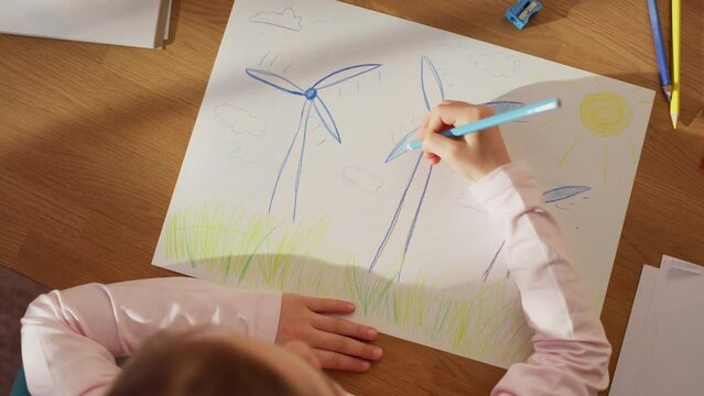 Top View: Little Girl Drawing Beautiful Wind Power Turbines that Look Like Flowers. On Sunny Day Smart Child Imagining Our Planet as a Happy Place with Clean, Sustainable Green Energy for Everyone