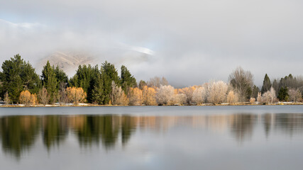 Fog lifting above Wairepo Arm of Lake Ruatuniwha, melting hoar frost reflected in the lake, Twizel, Canterbury.