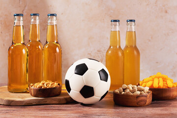 Beer and snack on wooden table with football ball, football game night food