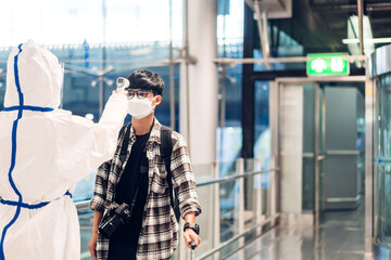 Doctor woman use infrared forehead thermometer for checking body temperature scan travel passenger fever in quarantine for coronavirus wearing safety protective mask at International terminal airport