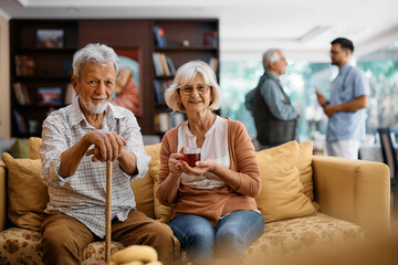 Happy senior couple at residential care home looking at camera.