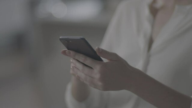 ungraded caucasian woman texting on a smartphone and moving in the chair, without showing screen, camera with movement