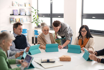 Group of seniors attending IT class in community centre with teacher