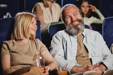 Mature Caucasian husband and wife spending evening together enjoying watching funny comedy movie at cinema