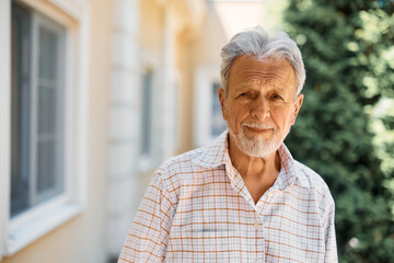 Portrait of senior man outdoors at nursing home looking at camera.