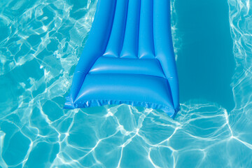 Bright blue summer pool lounger float on a rippled swimming pool