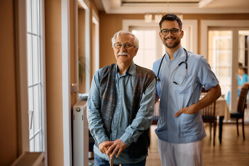 Happy male nurse and senior man at residential care home looking at camera.