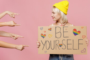 Young blond lesbian woman she wear colorful knitted top hat hold cardboard with be yourself title...