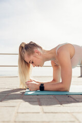 Blond woman practicing plank position on mat