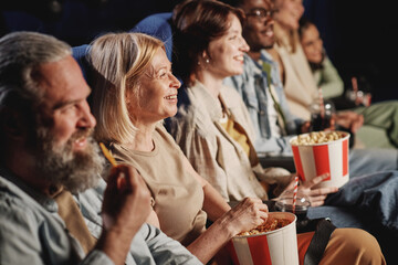 High angle of diverse group of people enjoying watching comedy movie and having snacks at cinema - obrazy, fototapety, plakaty