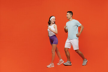 Fototapeta na wymiar Full body side view fun young fitness trainer instructor sporty two man woman in headband t-shirt run jog spend weekend in home gym isolated on plain orange background. Workout sport lifestyle concept