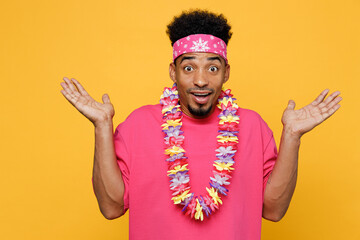 Young surprised amazed shocked impressed man 20s he in pink t-shirt hawaiian lei bandana near hotel...