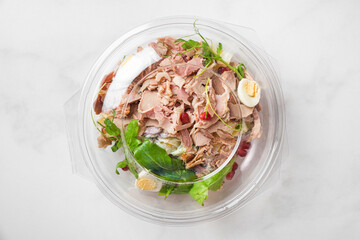 Plastic package with healthy baked ham salad for take away or food delivery on white background. Top view