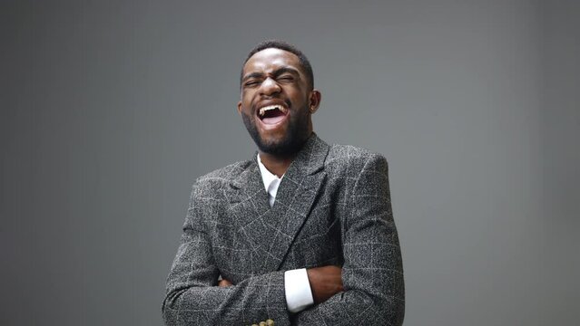 African american business man laughs hard and cackles on a gray background in the studio. Close-up slow motion video