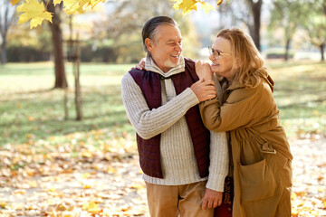 Senior woman and man walking together at the park during the autumn