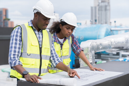 African American male engineer worker working with construction model building blueprint at construction site. Group of African American construction worker discussion about building blueprint