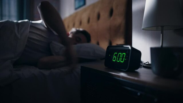 Handsome Man Wakes Up and Turns off Alarm Clock. Proceeds to Have a Productive Day of Work. Stylish Apartment. Focus on the Clock Showing Six O'Clock. Bedroom Apartment