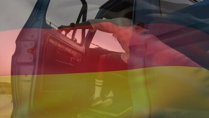 Animation of german flag waving over african american man getting in pick-up truck at beach - Powered by Adobe