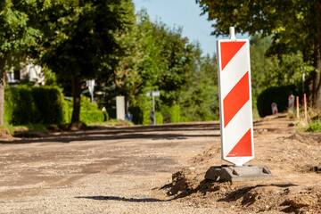 Red and white striped traffic control devices on the road being repaired