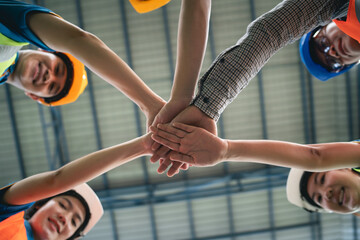 Group of industrial warehouse asian worker in safety suite hand stack celebrate successful or deal...