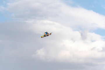 Flying quadcopter drone with blue cloudy sky in background. Low angle view of the multi-colored unmaned vehicle in the air.