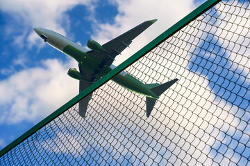 Plane taking off against the background of the fence and the border of the airport. Tourism, business, flight ban concept.