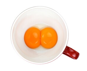 Two raw chicken eggs cracked into a bowl. Yolk and white without eggshells. Common food and versatile ingredient in cooking. Isolated macro food photo close up from above on white background.