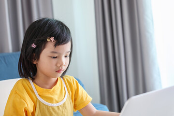 little asian girl student study online using laptop computer at home