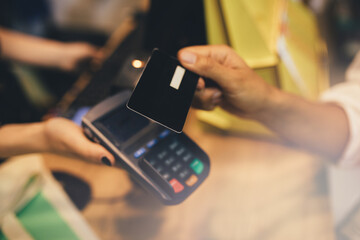 Young woman paying in a shop using credit card and terminal.
