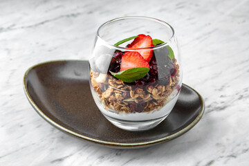 Healthy breakfast with oatmeal, yogurt, berries and nuts in a  plate on a marble background. Restaurant banquet menu.