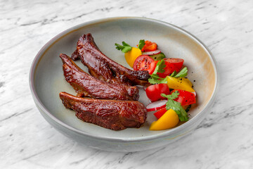 Pork, lamb, veal ribs in spicy-sweet sauce with vegetable salad in a  plate on a marble background. Restaurant banquet menu.