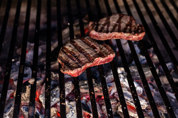 beef steak being grilled over hot coals on a barbecue. ready-to-eat food. food and nutrition concept