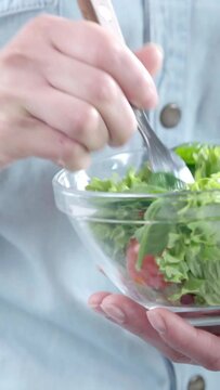 vertical video of cropped woman eating vegetable salad with fork