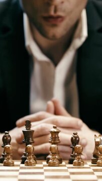 vertical video of cropped businessman playing chess and rubbing nose