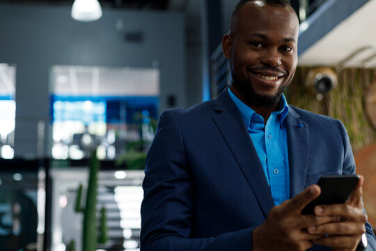 Happy businessman wearing suit using smartphone in office