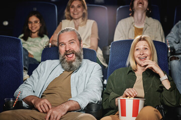 Group of people spending weekend at cinema watching funny comedy movie, selective focus shot