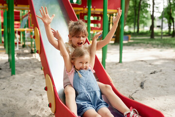 Fototapeta na wymiar Two cute girls have fun at playground in sunny day