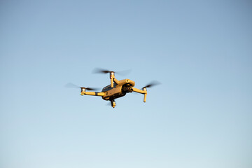 Fototapeta na wymiar Little Drone in Flight at Sunset on Blue Sky