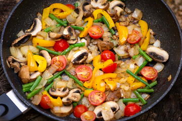 fried mushrooms with tomatoes, onions, asparagus and vegetables in a frying pan