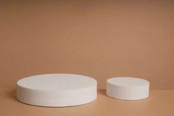 Abstract empty white podium with geometric shadows and pink flowers on blue background. Mock up stand for product presentation.Minimal concept. Advertising template