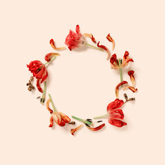 A wreath of fading flowers and petals is on a beige background. The concept of aging and fading. Composition in autumn colors. Flat lay. Top view. Copy space.