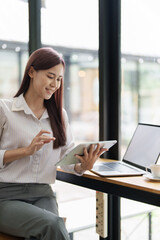 Portrait of an Asian female employee using a tablet computer at work.