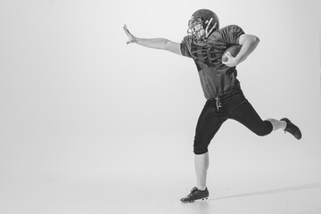 Fototapeta na wymiar Dynamic portrait of american football player in action and motion isolated on white background. Concept of sport, achievements, retro style. Monochrome