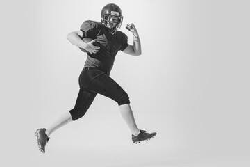 Fototapeta na wymiar Dynamic portrait of american football player in action and motion isolated on white background. Concept of sport, achievements, retro style. Monochrome