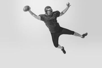 Fototapeta na wymiar One american football player wearing retro stlye sports uniform in action and motion isolated on white background. Monochrome