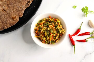 Super spicy green and red bird eye chili chutney using lal and hari mirch, garlic cloves, and coriander. served in a white bowl. Also known as Thecha in Marathi served with Raagi roti. copy space