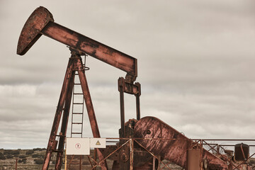 Rusty oil pumping machine. Pump jack. Petroleum extraction. Global warming